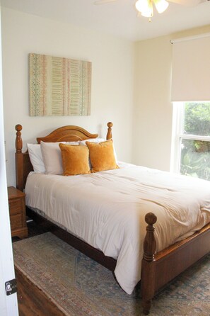 A bedroom with a wooden bed, white bedding, and a patterned rug. - Aryn Ridge House / 3BR / Near Casinos & Interstate (Lake Charles)