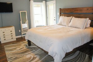 A bedroom with a bed, a dresser, a mirror, and a television on the wall.
