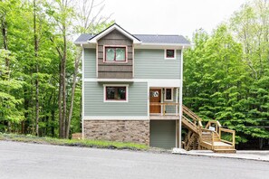 A two-story building with a stone foundation, a wooden staircase, and a front door. - Tremendous 2-bedroom cottage in Beech Mountain North Carolina (Banner Elk)