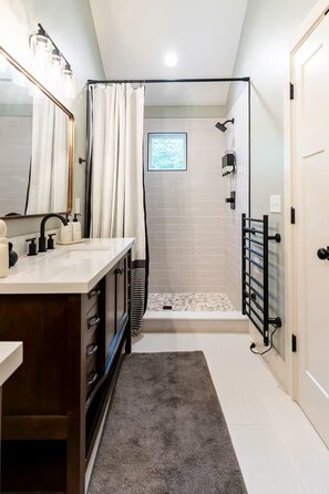 A modern bathroom with a shower, a vanity with a mirror, and a towel rack. - Tremendous 2-bedroom cottage in Beech Mountain North Carolina (Banner Elk)