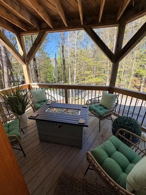 A wooden deck with a fire pit table, green cushioned chairs, and potted plants. - Tremendous 2-bedroom cottage in Beech Mountain North Carolina (Banner Elk)