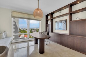 A modern office space with a large table, a chair, and a hanging light fixture. - Stunning Beachfront Penthouse | Luxury Living & Gulf Views (Naples)