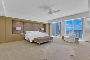 Una camera da letto con un letto, comodini, una ventola a soffitto, una grande finestra vista e un balcone con una sedia.
