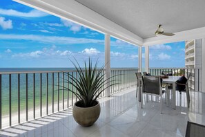 Un balcone con vista sull'oceano, una pianta in vaso e una zona pranzo con sedie e tavolo.