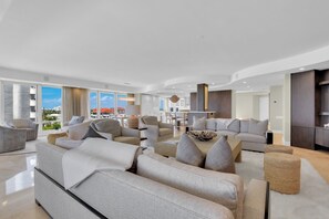 Ein modernes Wohnzimmer mit einer großen Sofagarnitur, einem Couchtisch und einem Essbereich mit Stühlen.