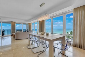 Zona pranzo moderna con vista sul mare, un balcone e un'ampia finestra.