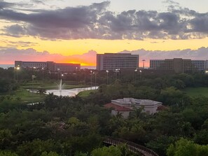 Un hôtel offrant une vue sur le coucher de soleil, une fontaine et la verdure environnante.
