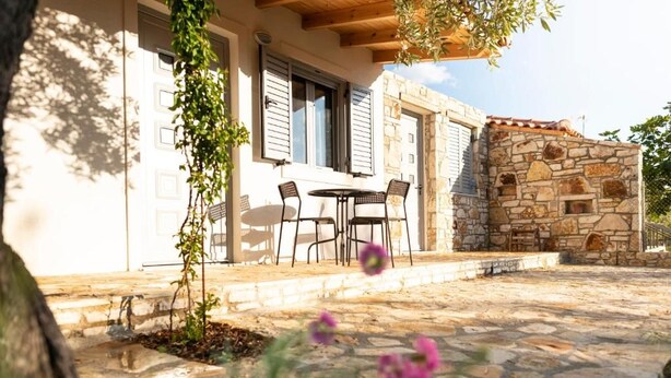 Un edificio de piedra con un patio, mobiliario exterior y un muro de piedra.
