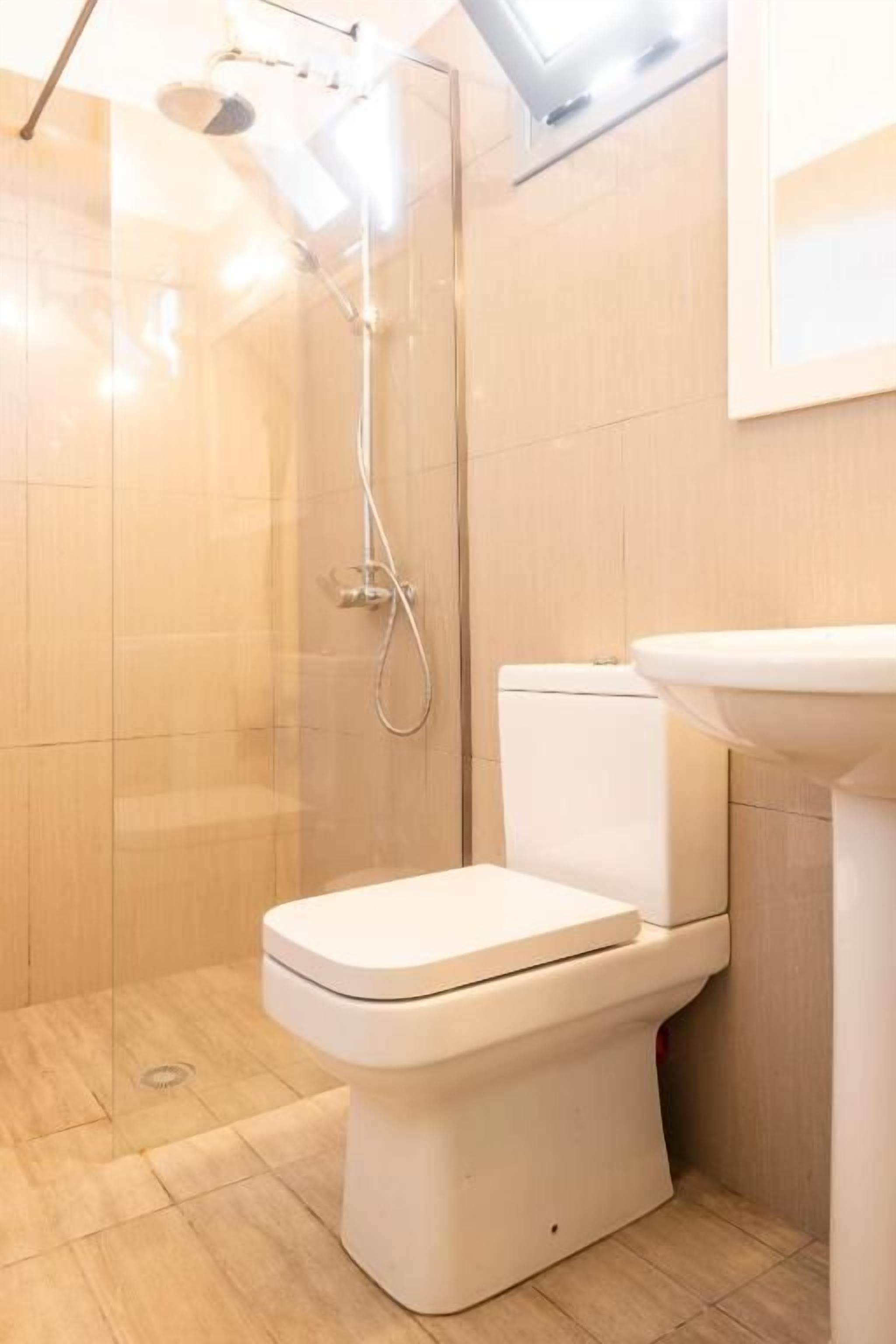 A bathroom with a toilet, a shower, and a sink.