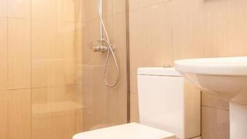A bathroom with a toilet, a shower, and a sink.