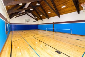 Una cancha de baloncesto interior con suelo de madera, paredes azules y un aro de baloncesto.