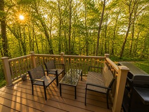 A deck with outdoor furniture and a grill, surrounded by a forest. - Pecker’s Nest  Cozy Cottage in Galena Territory (Galena)