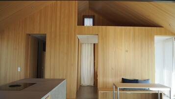 Ein modernes Interieur mit Holzvertäfelung, einer Küchenzeile, einem Essbereich und einem kleinen Fenster.