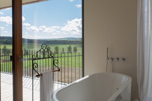 Ein Badezimmer mit einer Badewanne, einer Dusche und Blick auf eine grüne Landschaft vom Balkon aus.