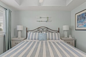 A bedroom with a bed, two bedside tables, a nightstand, a painting, and a window with curtains. - Destin West Gulfside 205 ~ Ocean Views ~ Beach Service Included (Fort Walton Beach)