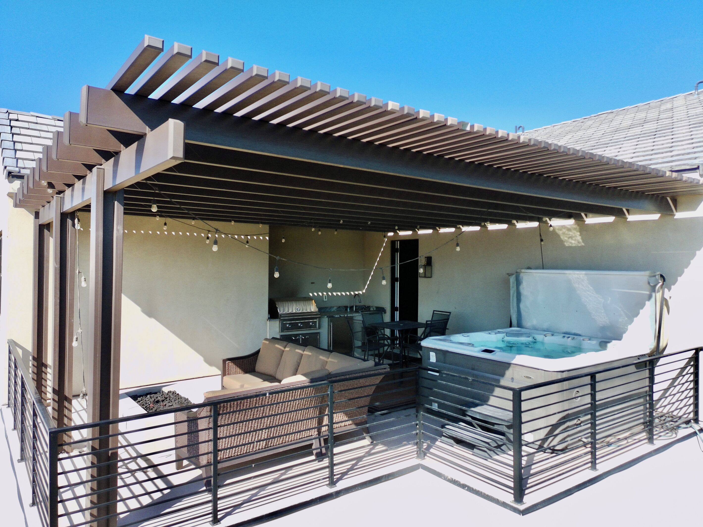 Un espacio de estar al aire libre techado con un jacuzzi, un sofá y una mesa.