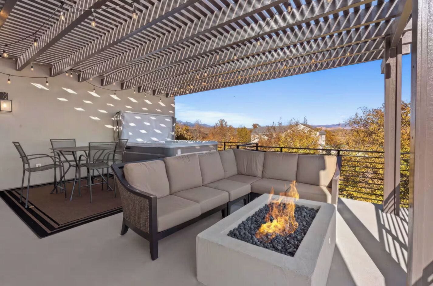 An outdoor patio with a sectional sofa, a fire pit, a grill, and a dining area.