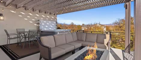 An outdoor patio with a sectional sofa, a fire pit, a grill, and a dining area.