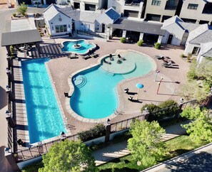A residential area with a swimming pool, lounge chairs, and a fountain. - Desert Sands Basecamp | Hot Tub | Pool | Fire Pit (Hurricane)