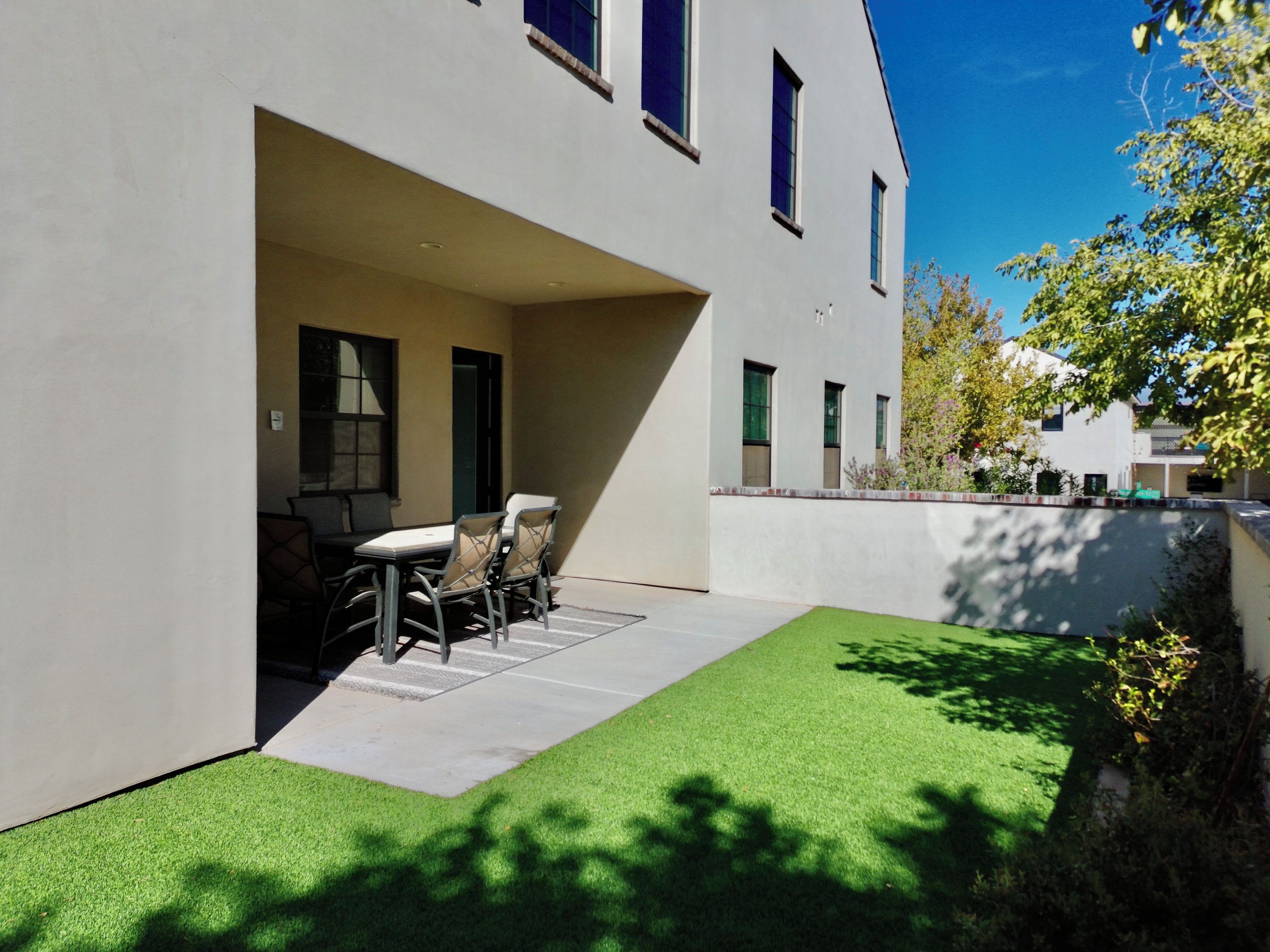 A modern building with a patio area featuring a table and chairs, surrounded by a well-maintained lawn.