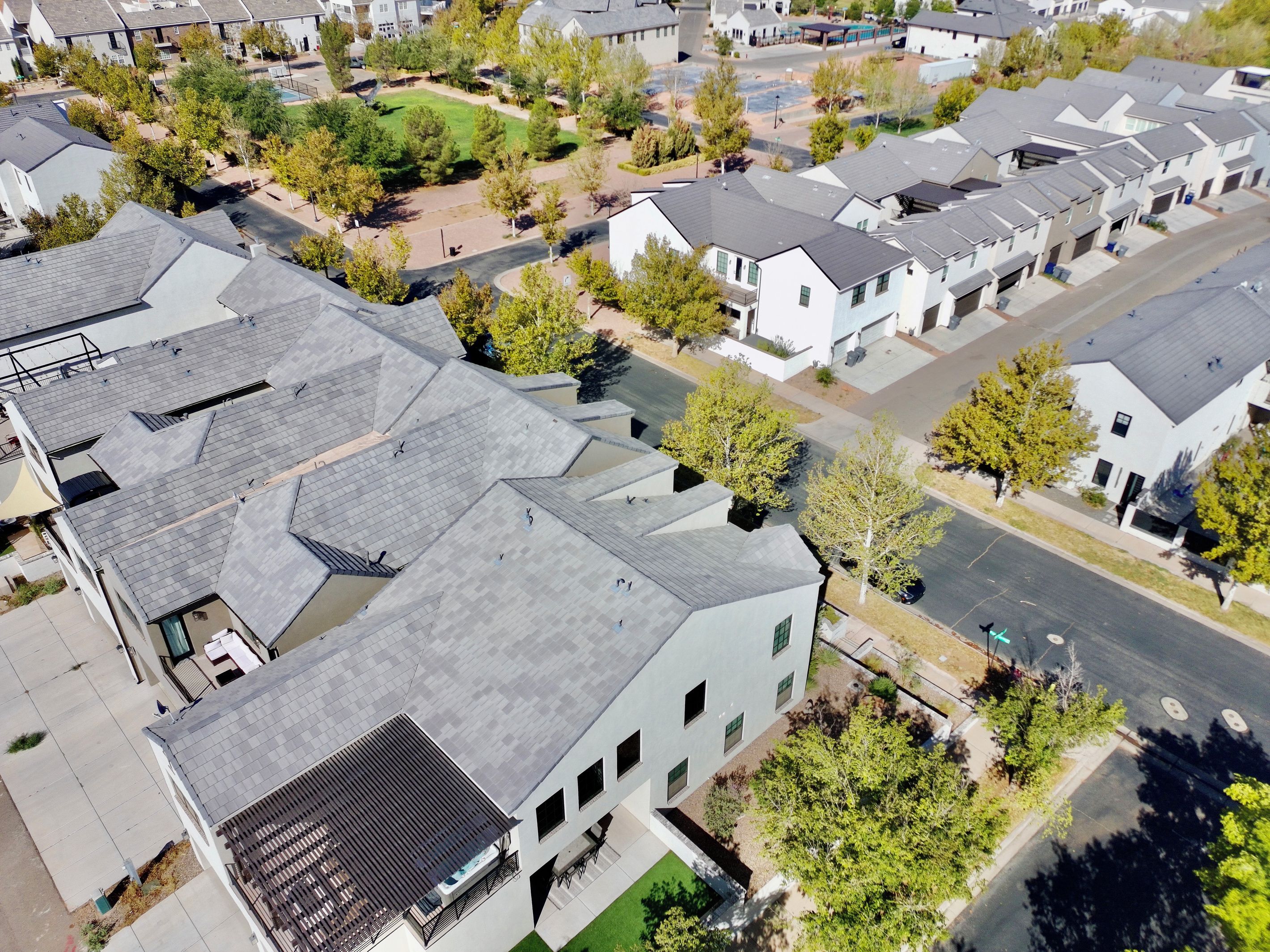 A residential area with multiple two-story houses, a central grassy area, and a main road.