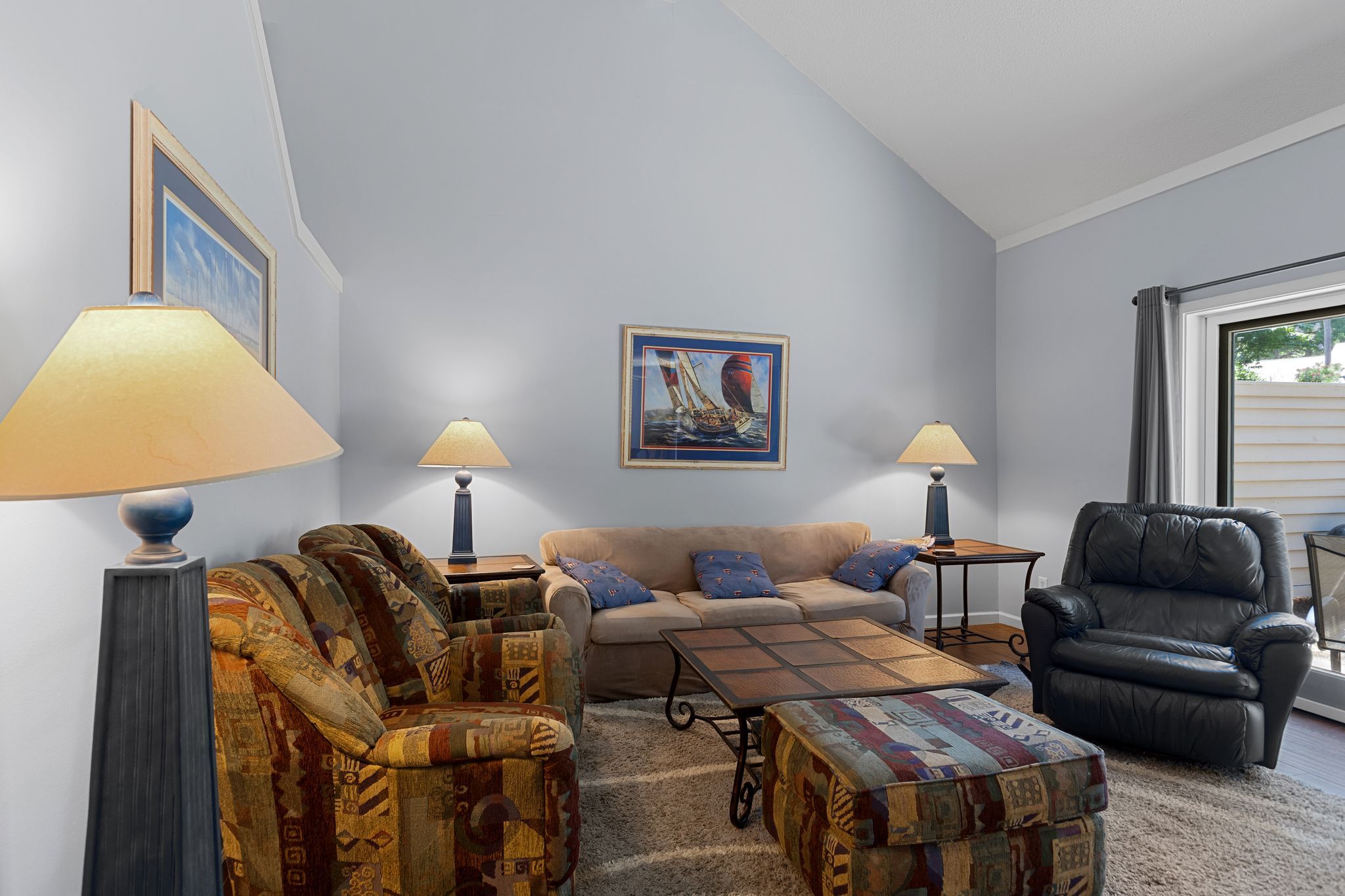 A living room with a sofa, armchairs, a coffee table, and two floor lamps.