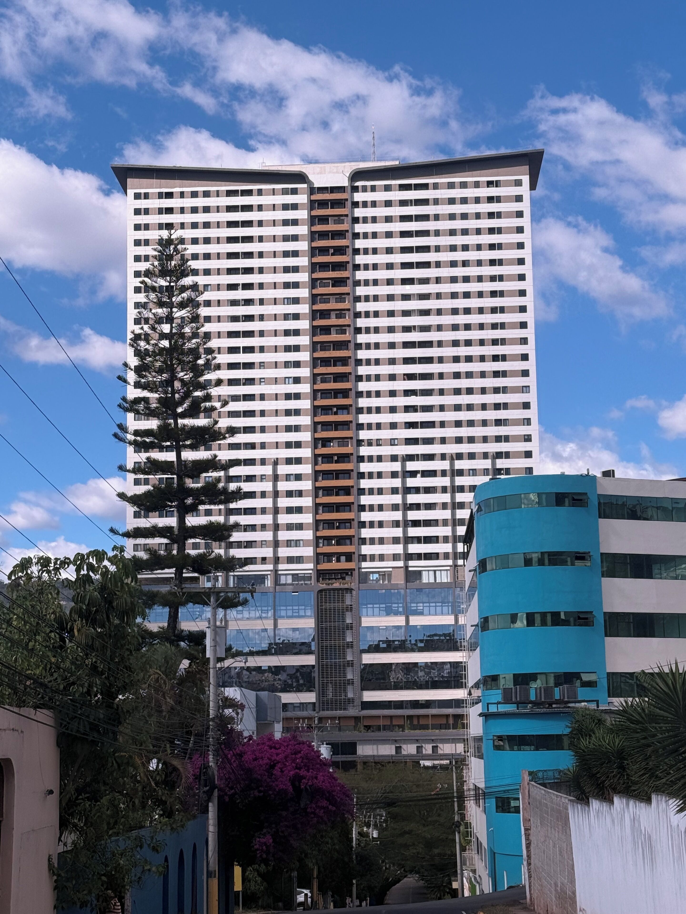 A high-rise building with multiple floors, a central elevator shaft, and a reflective glass facade.