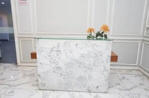 En receptionsdisk med en marmorskiva, två blomvaser och en skylt med texten ”Rökning förbjuden” på väggen.
