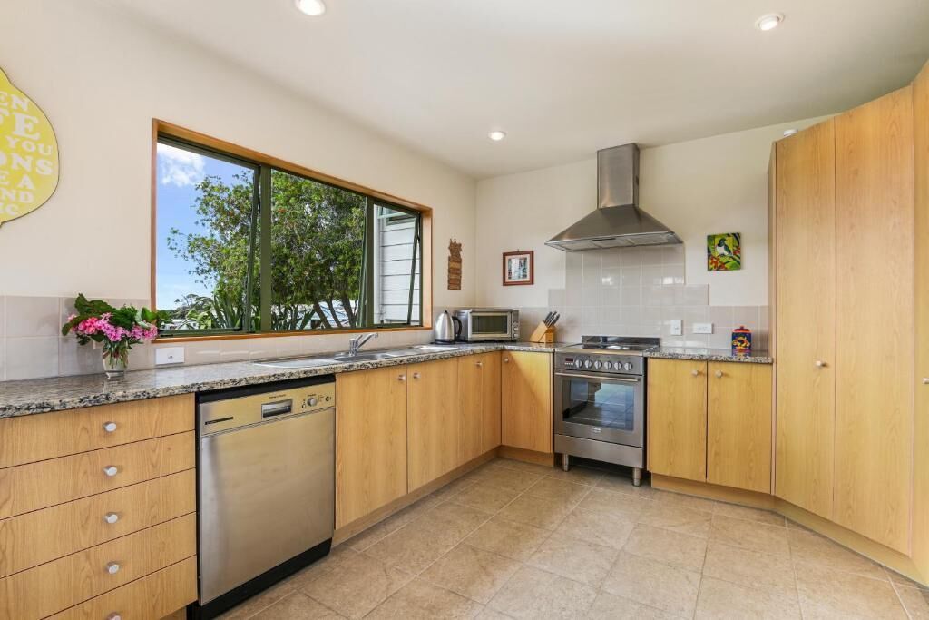 A modern kitchen with wooden cabinets, a dishwasher, a microwave, and an oven.