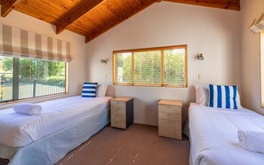 A bedroom with two beds, a window with blinds, and a ceiling with wooden beams. - Coastal Calm by Waiheke Pure -Central, views, peaceful (Waiheke Island)