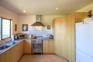 A compact kitchen with a stove, microwave, and sink. - Coastal Calm by Waiheke Pure (Waiheke Island)