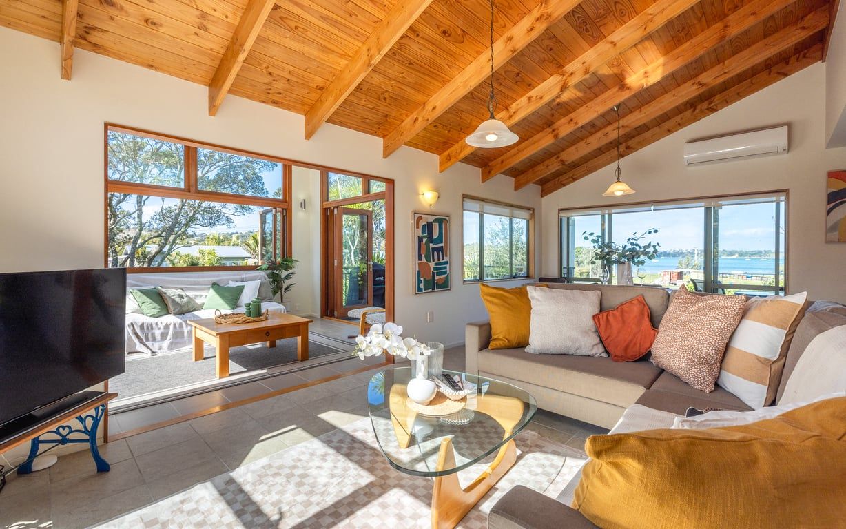 A spacious living room with a large TV, comfortable seating, and large windows offering a view of the outdoors.