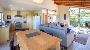 Una cocina moderna con vigas de madera, un comedor con mesa y un espacio de sala con sofá.