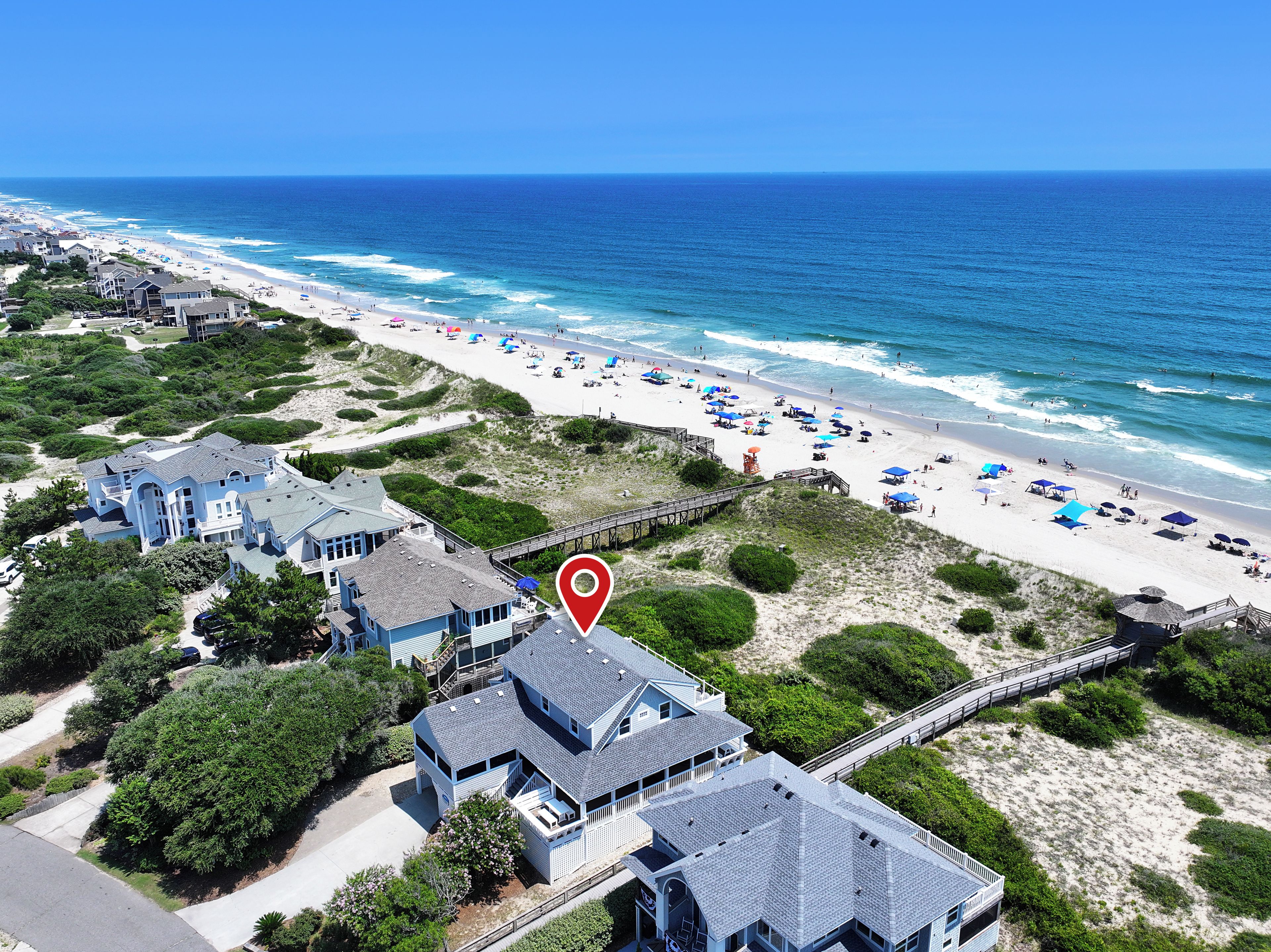A coastal property with a beach view, a pier, and a large house with multiple decks.