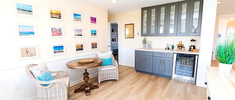 A modern kitchen with grey cabinets, a built-in fridge, and a dining area with wicker chairs and a round table.