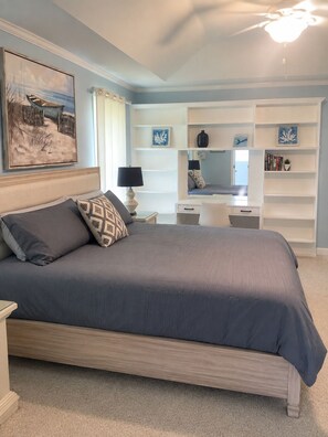 Ein Schlafzimmer mit Bett, Nachttischen, Schreibtisch und Regalelement.