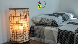 Huoneessa on perinteinen japanilaistyylinen lämmitin, kuviollinen vuodevaatteilla varustettu sänky ja seinä, jossa on värikäs logo.