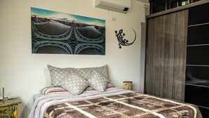 Ein Schlafzimmer mit einem Bett, Kissen mit Muster, einem Wandbild und einem Kleiderschrank.