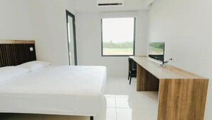 A hotel room with a bed, a desk, a chair, and a television. - Omega Rooms Riverdale by Buka Kamar (Cikarang/Bekasi)