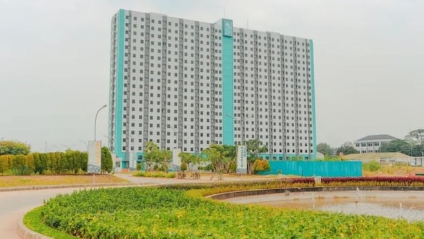 A high-rise building with a uniform facade, surrounded by landscaped areas and a water feature. - Omega Rooms Riverdale by Buka Kamar (Cikarang/Bekasi)