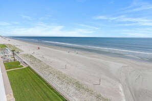 En strand med klar himmel, en sandstrand och några få personer.