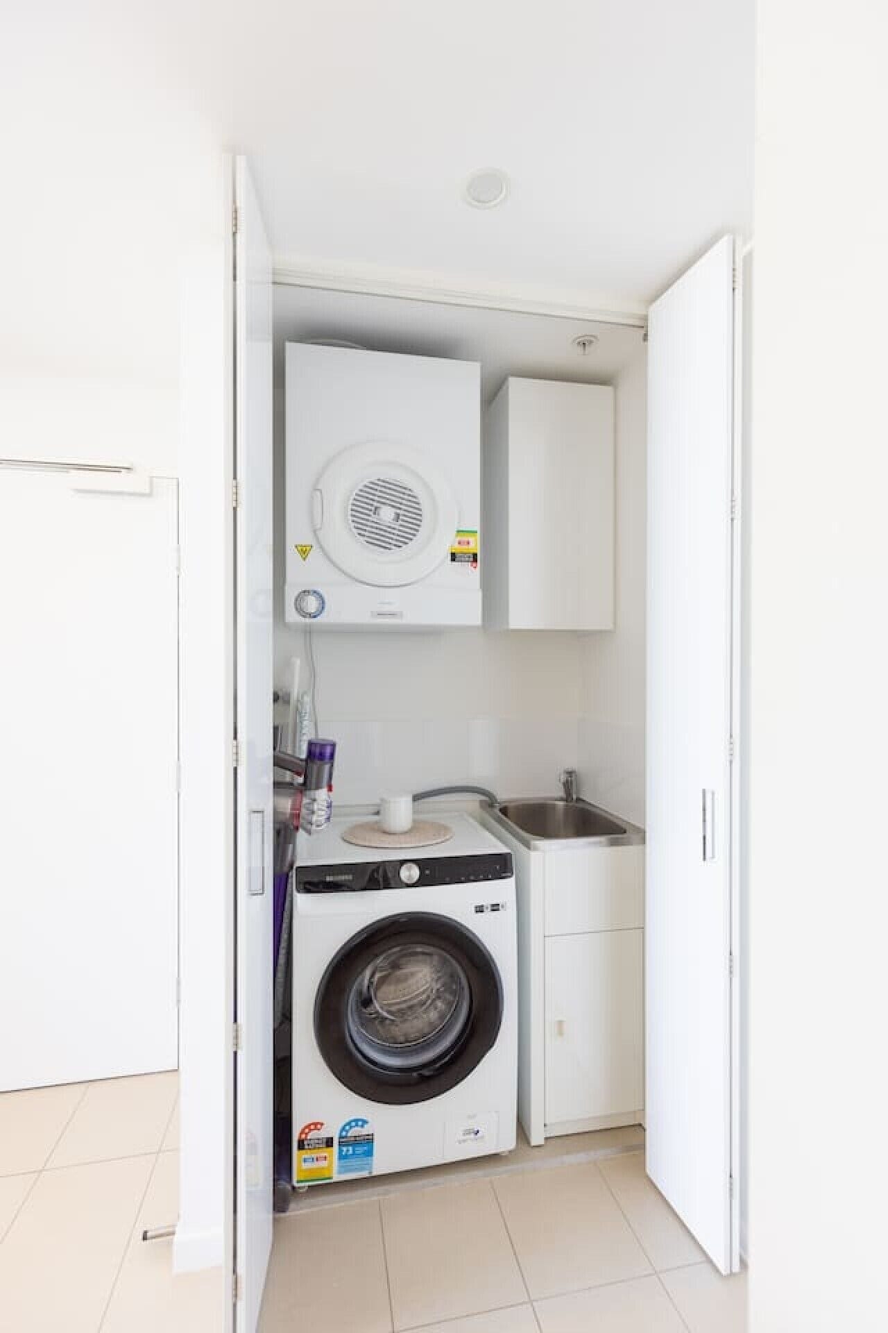 Ein kleiner Hauswirtschaftsraum mit Waschmaschine, Trockner und Spüle.