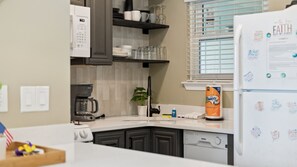 A kitchen with a coffee maker, a refrigerator with magnets, and a plant. - Gulf Highlands Studio Getaway | King Bed, Bunks, Steps to the Beach (Panama City Beach)