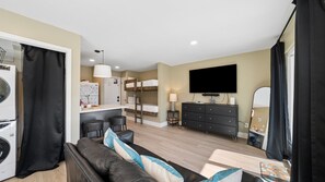 A compact living space with a kitchenette, a sofa, a TV, and a bunk bed. - Gulf Highlands Studio Getaway | King Bed, Bunks, Steps to the Beach (Panama City Beach)