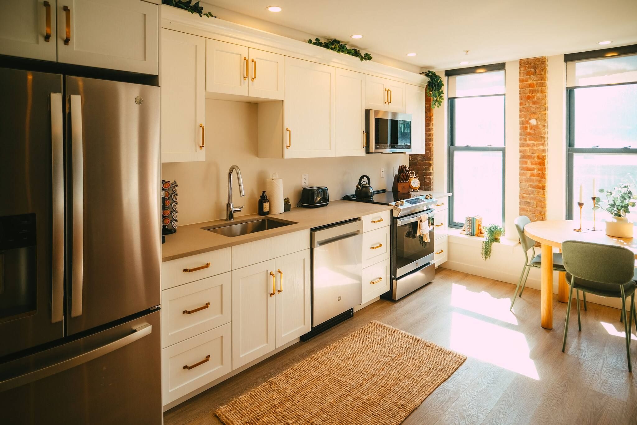 A modern kitchen with stainless steel appliances, white cabinetry, and a dining area with a table and chairs.