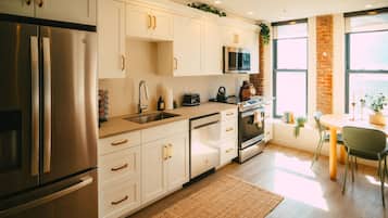 A modern kitchen with stainless steel appliances, white cabinetry, and a dining area with a table and chairs.