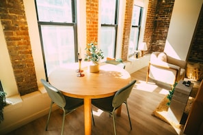 Une table ronde en bois, accompagnée de deux chaises, d’une plante en pot et d’une bougie.