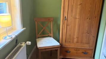 A room with a radiator, a wooden chair, and a wooden cabinet.