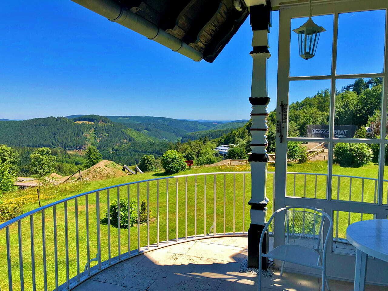 Un balcon donnant sur un paysage vallonné, avec une table et une chaise.