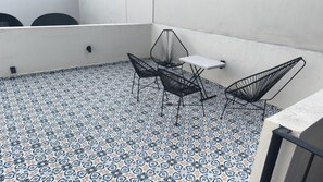 A balcony with patterned floor tiles, a small table, and two chairs. - Apartment with a large terrace in the heart of Guadalajara, (Guadalajara)